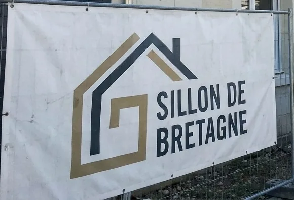 Bâche Sillon de Bretagne Toitures sur une clôture de chantier de couverture à Couëron