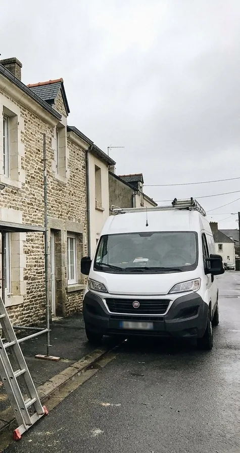 Échafaudage, échelle et camion de couvreur devant une maison en pierre d'une rue de Couëron